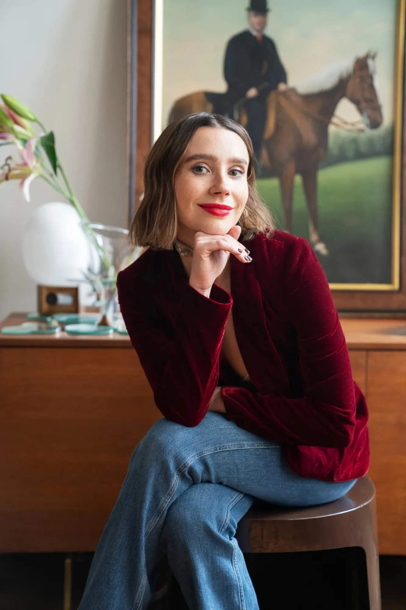 Amanda Montell in a red velvet blazer, chin resting on her hand